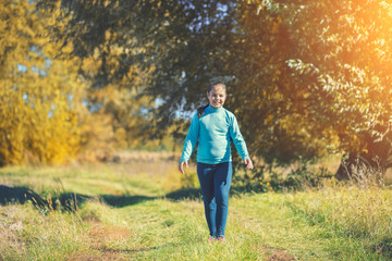 Happy little girl walking  along the rural road in the countryside