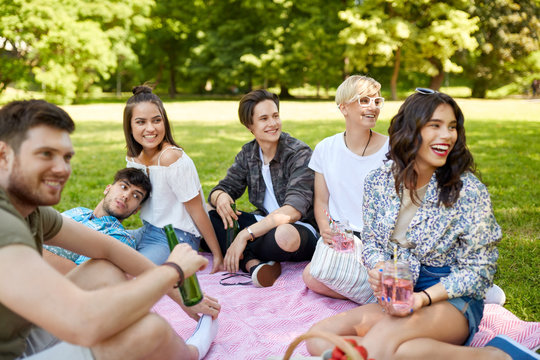friendship and leisure concept - group of happy friends with non alcoholic drinks at picnic in summer park