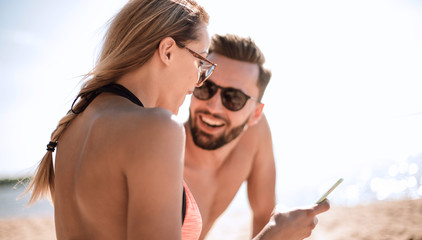 Smiling couple browsing their photos on the beach
