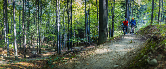Mountain biking women and man riding on bikes in early spring mountains forest landscape. Couple...