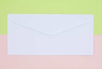 white envelope on green and pink paper background.