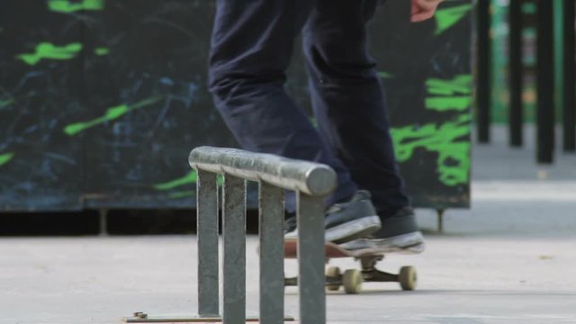 Skater rides on a rail with trick 50-50 grind, close-up view in slowmotion
