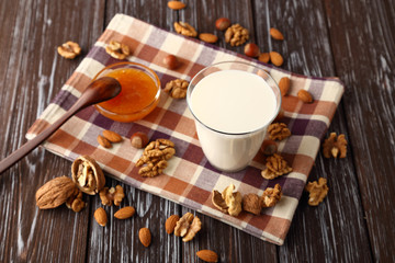 A glass of fresh milk with almonds, hazelnuts, walnuts and honey.