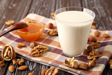 A glass of fresh milk with almonds, hazelnuts, walnuts and honey.