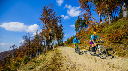 Cycling, mountain biker couple on cycle trail in autumn forest. Mountain biking in autumn landscape...