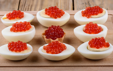 Red caviar on halves of hard-boiled chicken eggs on a cutting board