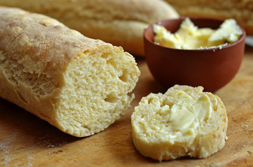 A baguette spread with butter on a wooden board