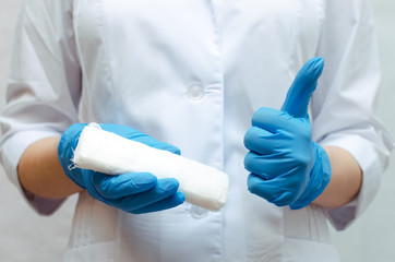 Medical bandage in the doctor hands dressed in the blue medical gown.