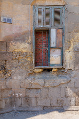 Fototapeta na wymiar Broken windows and grunge stone bricks wall in abandoned Darb El Labana district, Cairo, Egypt