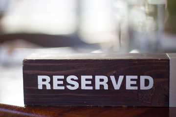 Reserved wooden Card Plate on the Table with Blurry background. Reservation Seat at restaurant. - leisure, people and service concept