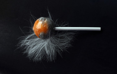 fluffy lollipop. Caramel in white woolly wool on a black background. dirty candy