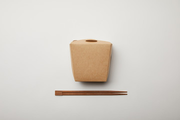 elevated view of arranged chopsticks and noodle box on white surface, minimalistic concept