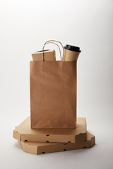 pizza boxes and food delivery paper bag with disposable coffee cup and wok box on white