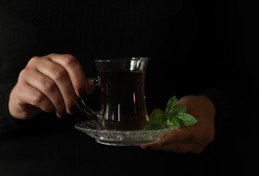 Cup of spearmint tea on a tray in the hands of a woman.