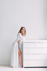 Conceptual wedding, the morning of the bride in the European style. Boudoir dress and a bouquet of flowers, fees in the interior Studio. White minimalism for the bride