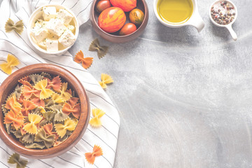 Pasta food cooking concept. Ingredients for preparation pasta - tomato, olive oil, spices, olives, tomato, grey wooden background. Top view with copy space for text.