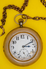 Pocket vintage gold watch on a yellow background.