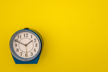 An old alarm clock on a yellow background.