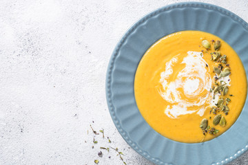 Pumpkin cream soup on light stone table.