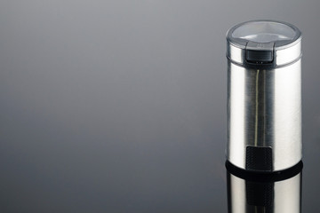 Coffee grinder on the grey mirror background