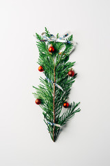 top view of green pine branch decorated with christmas toys and ribbon as christmas tree on white backdrop