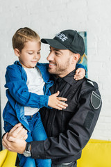 handsome young father in police uniform carrying his little son