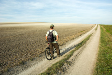 Fototapeta na wymiar Man traveler and bike on a country road