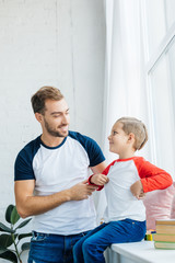 Fototapeta premium portrait of smiling man and adorable son at home