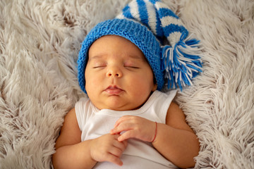 Fototapeta na wymiar child, happiness and childhood concept - sleeping little baby in blue hat.