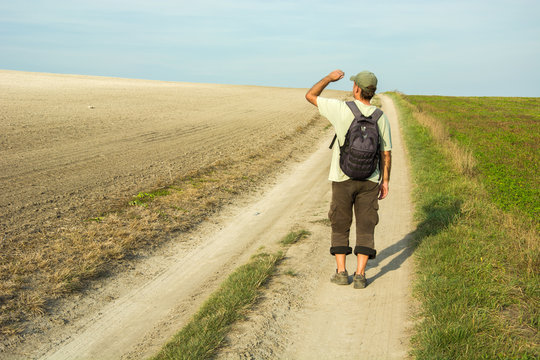 Man, traveler on a dirt road looking to the horizon.