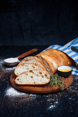 Sliced homemade italian ciabatta bread with olive oil on dark background. Ciabatta, herbs, olive...