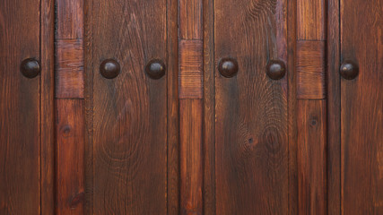Cropped, ornate cherry-brown wooden door with metal studs, a medieval, rustic or antique design. Ornamental  background concept for home ownership, status, privacy or interior design with copy space