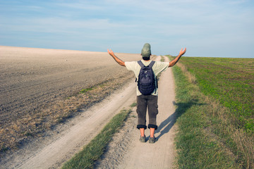 Fototapeta premium Man traveler on a dirt road with hands up
