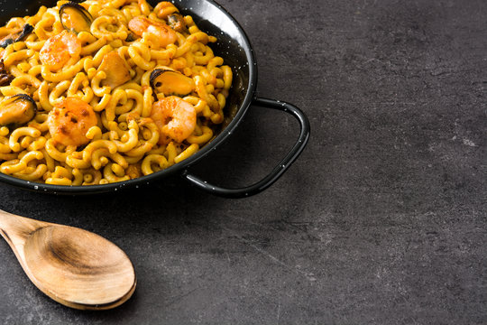 Traditional Spanish fideua. Noodle paella on black stone. Copyspace