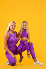 Mother and daughter exercise together indoors. Family look.