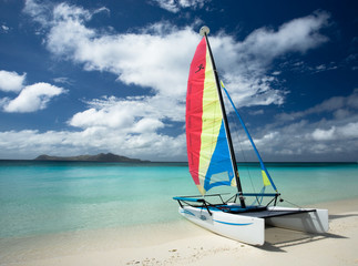 Katamaran, water sports on tropical beach with chrystal clear turquoise blue waters, island in distance