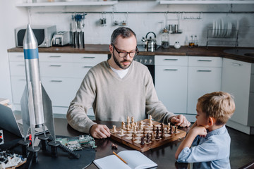 high angle view of father and little son playing chess together at home