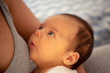 Portrait of beautiful baby with blue eyes in mother’s arms- child, happiness and childhood concept.