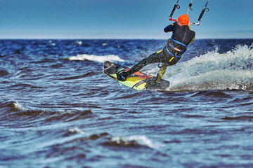 A male kiter slides on the surface of the water. Splashes of water fly apart. Close-up.