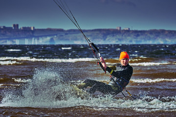 A male kiter slides on the surface of the water. Splashes of water fly apart. Close-up.
