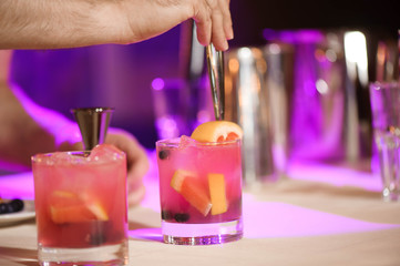 Expert barman is making cocktail at night club.