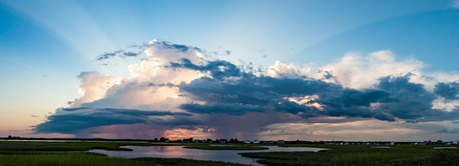 Summer raincloud over the marsh with sun setting