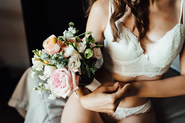 Sexy beautiful nude brunette bride with bouquet and wavy hair style in white erotic underwear. - obrazy, fototapety, plakaty