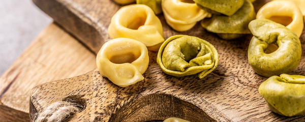 Homemade Tortellini with spinach, cheese and ricotta on wooden board. Gluten free italian food concept. Banner.