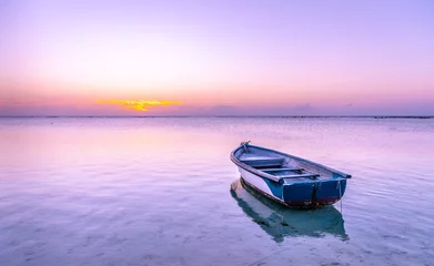 Fototapeten Mauritius Boat in the sea with pink and purple colors during Sunset in beautiful Mauritius paradise landscape. Mauritius nature view of colorful sky and light of sun. Reflection on the sea near beach © mbrand85