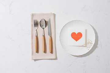 love dinner setting fork and spoon tie with red ribbon on plate on white background , love and romance concept