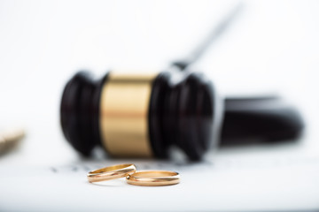 Divorce decree, gavel and wedding rings.