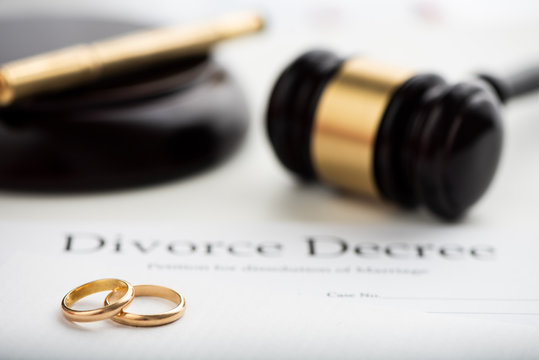 Divorce decree, gavel and wedding rings.
