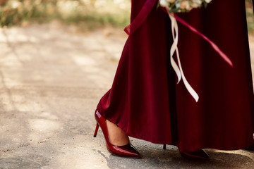 Fototapeta na wymiar red stiletto shoes and bridesmaid dress with a bouquet of different colors