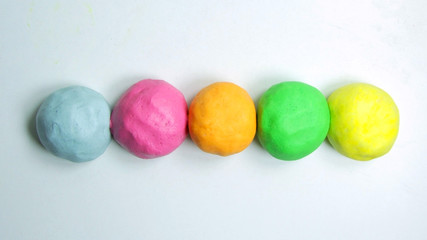 Fototapeta na wymiar Close up of homemade colorful playdough on a white table.